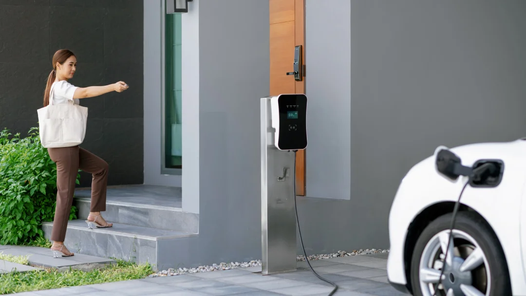 Une femme recharge sa voiture à une station de recharge pour véhicules électriques à domicile.