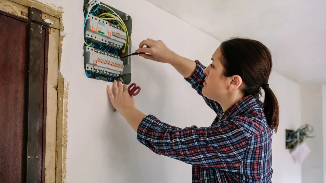 Une personne tient un interrupteur sur un panneau électrique, se préparant à modifier les paramètres du panneau.