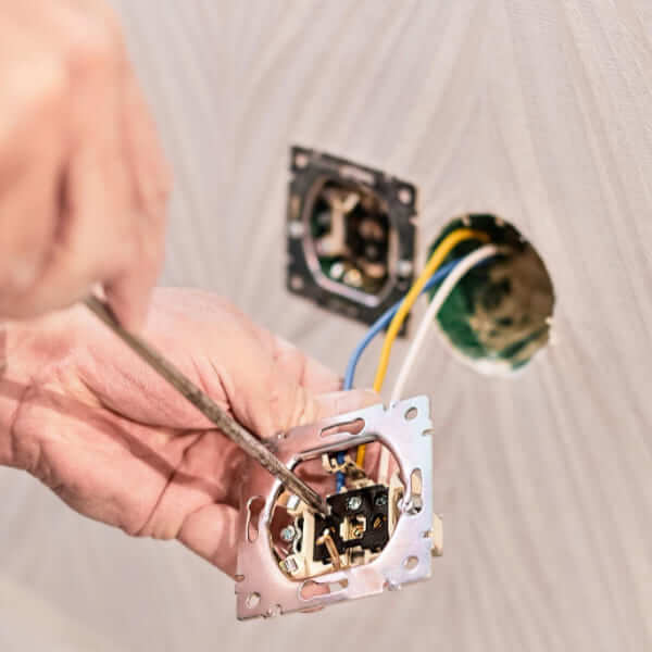 Un électricien professionnel en train d'installer soigneusement une borne de recharge électrique sur un mur.