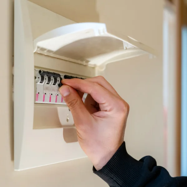 Une personne réglant un interrupteur électrique sur un mur, concentrée sur le changement du panneau électrique.