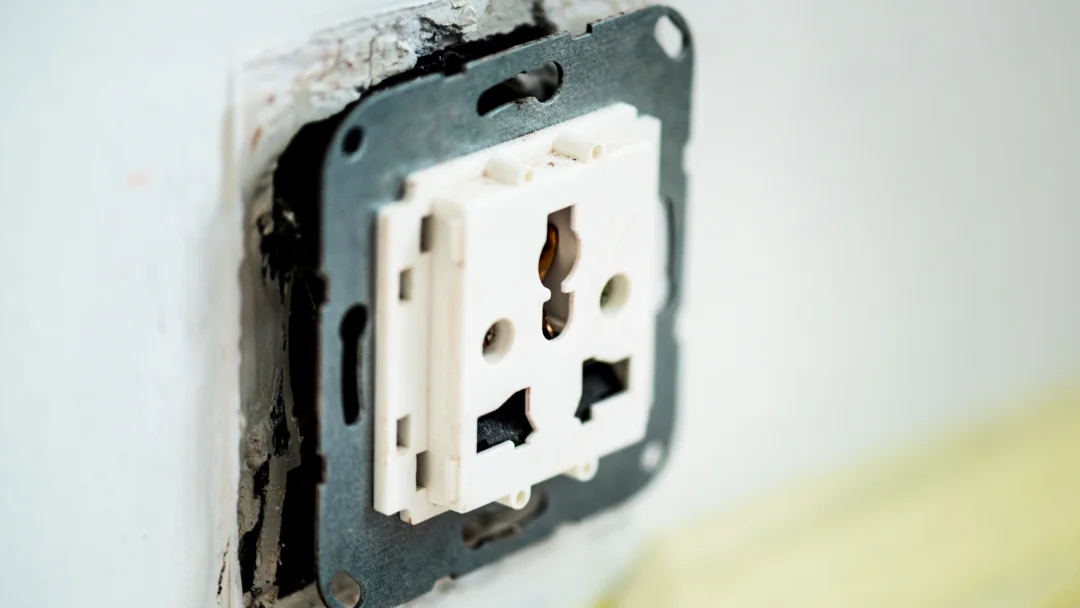 Prise électrique blanche avec une fiche noire insérée.