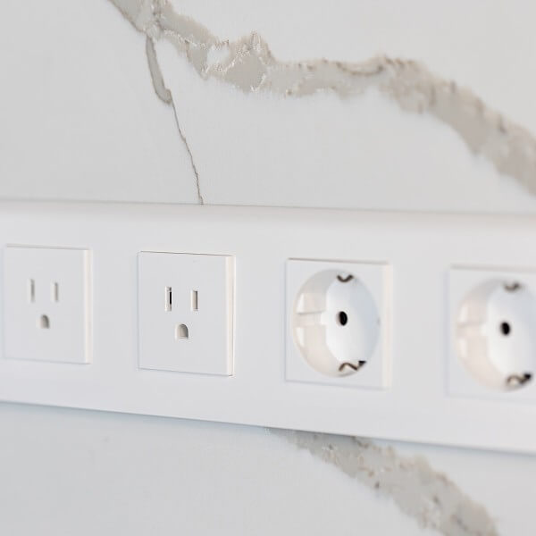 Prises électriques mixtes sur un mur en marbre blanc.